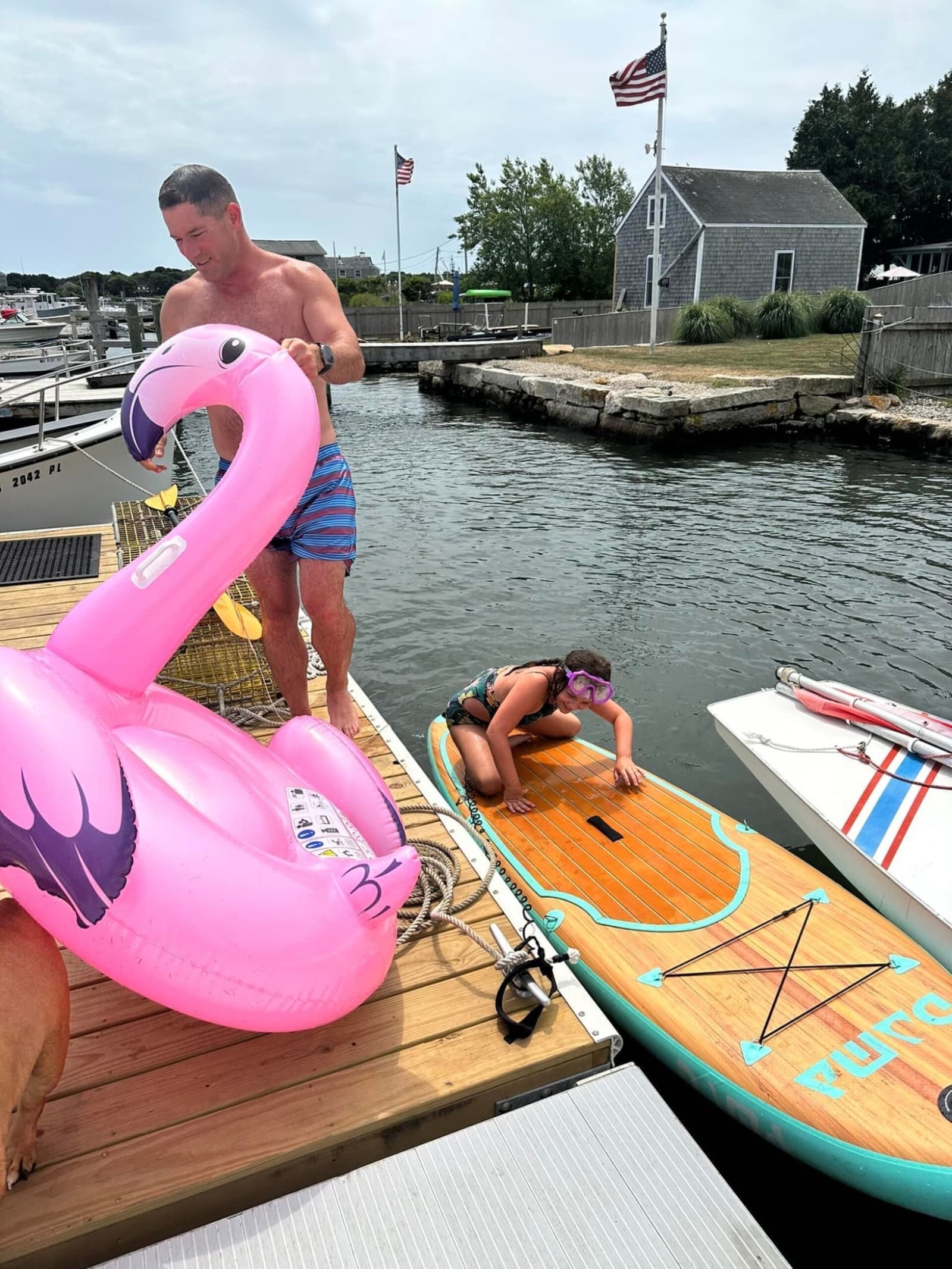 Pink flamingo float and kid on paddleboard with snorkel gear at the dock