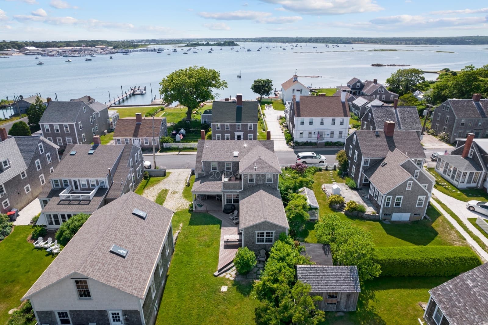 Aerial view of Westport Point village showing shingled houses, green lawns, harbor moorings, and a cupola